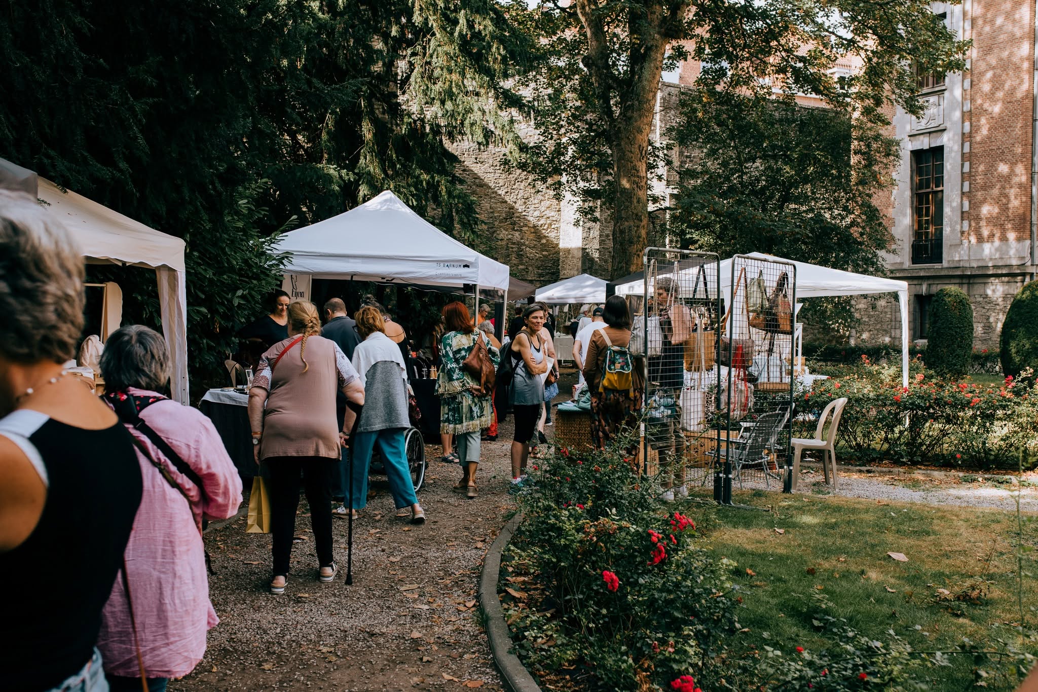 Visiteurs découvrant les stands d’un marché de créateurs dans un jardin